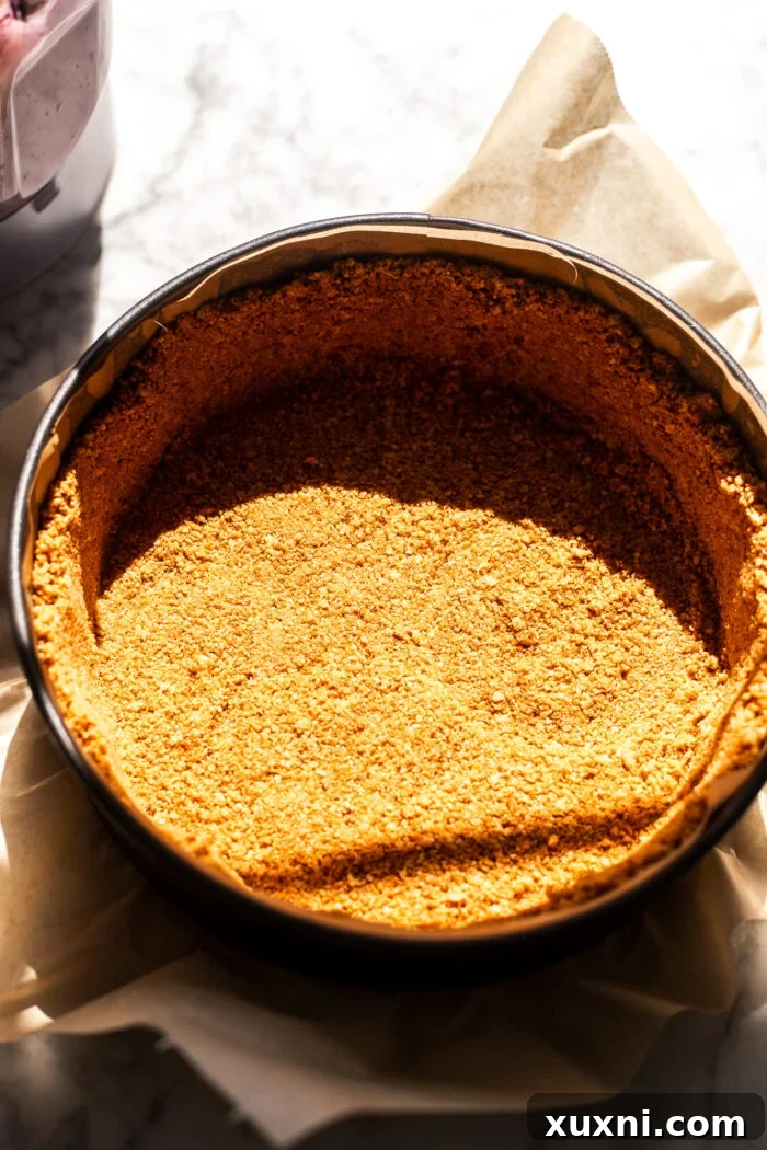 The graham cracker crust mixture pressed firmly into the bottom and sides of a springform pan.