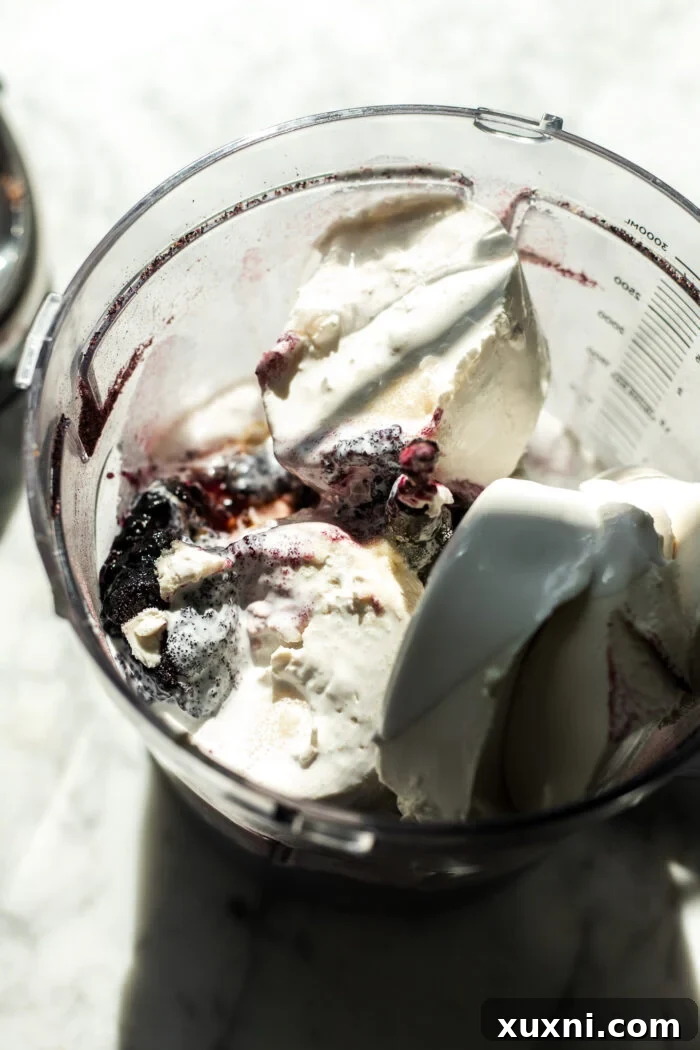 All blueberry cheesecake filling ingredients being added into a food processor for blending.
