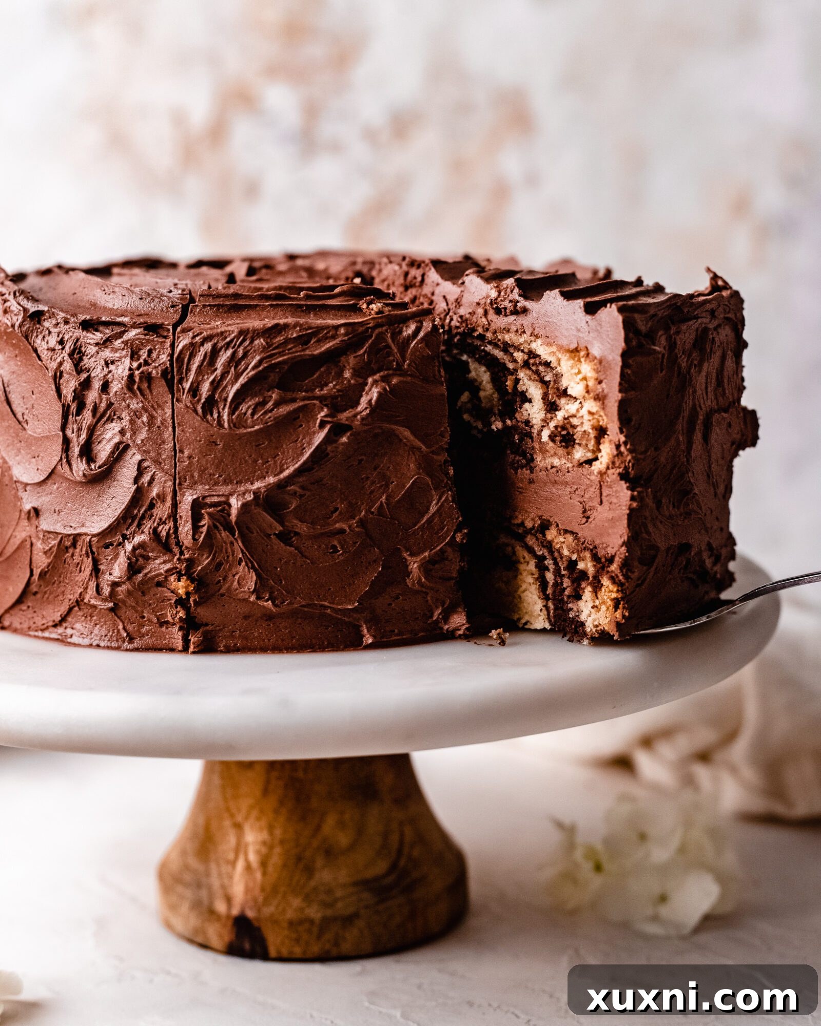 A fully frosted and sliced vegan zebra cake on a cake stand, ready to be served.