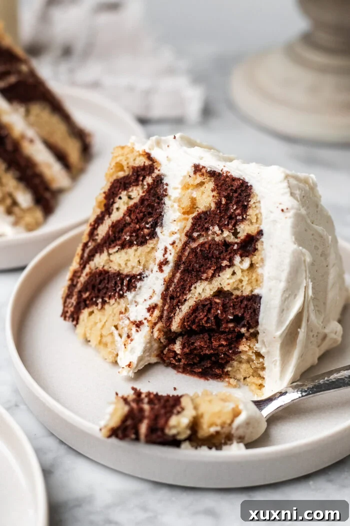 A slice of vegan zebra cake with a bite taken out, showing the moist interior and cream cheese frosting.