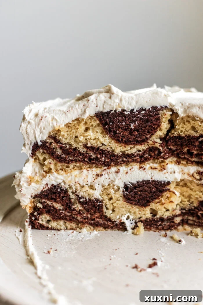 A beautifully sliced whole vegan zebra cake on a serving platter, showing off its perfect stripes.
