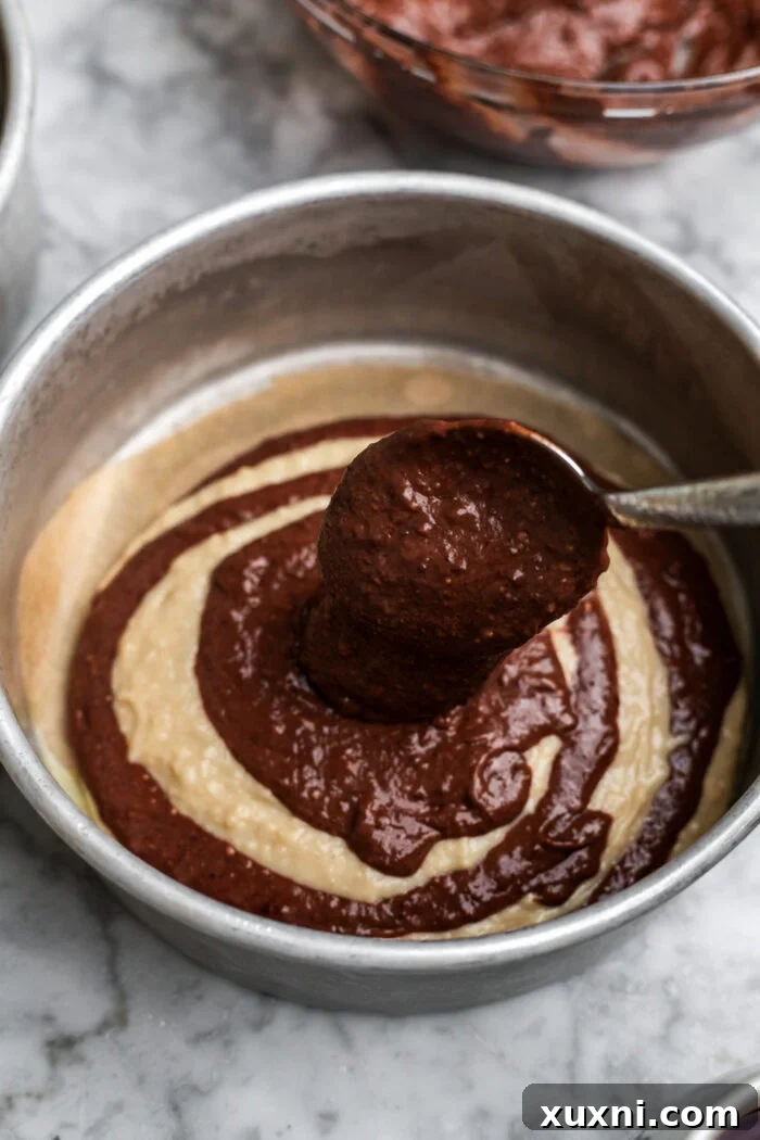 Close-up of the initial batter layering in a cake pan for the zebra pattern.