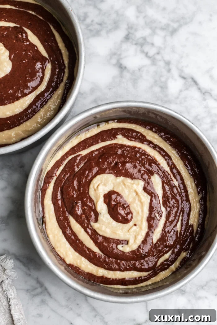 Vegan zebra cake batter in pans before baking, showing the distinct concentric layers.