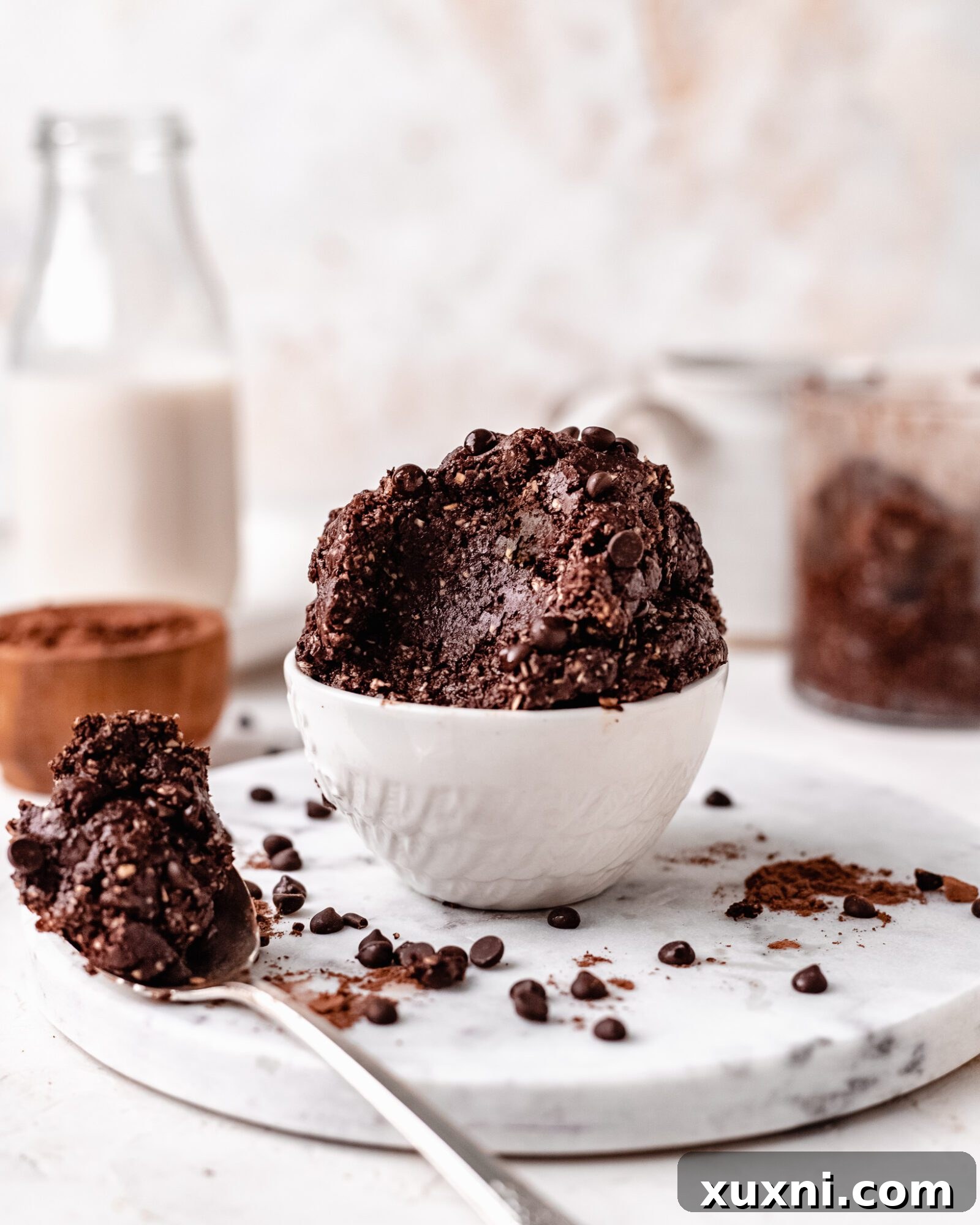 A small cup of healthy edible brownie batter, topped with a few chocolate chips, ready to be enjoyed.