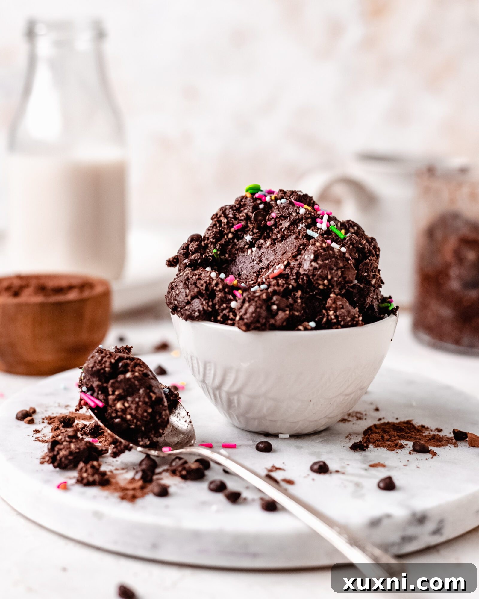 A bowl of healthy edible brownie batter generously topped with colorful vegan sprinkles, ready to be enjoyed.