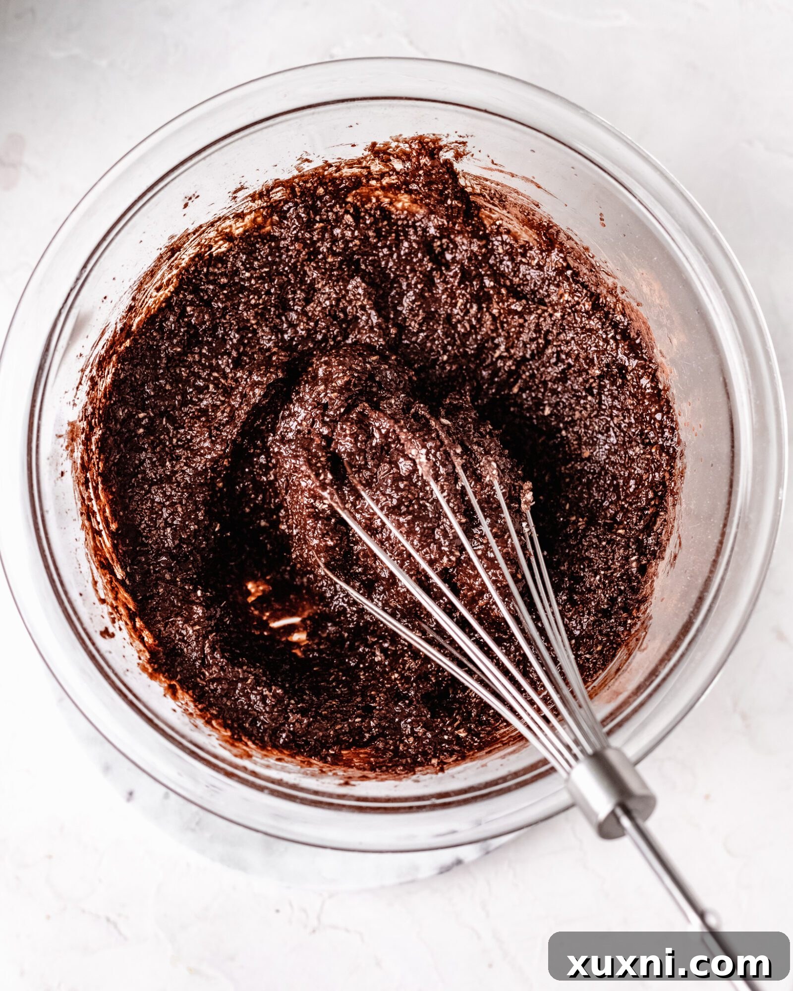 Smooth chocolate mixture with applesauce just added, being whisked into the vegan brownie batter base.