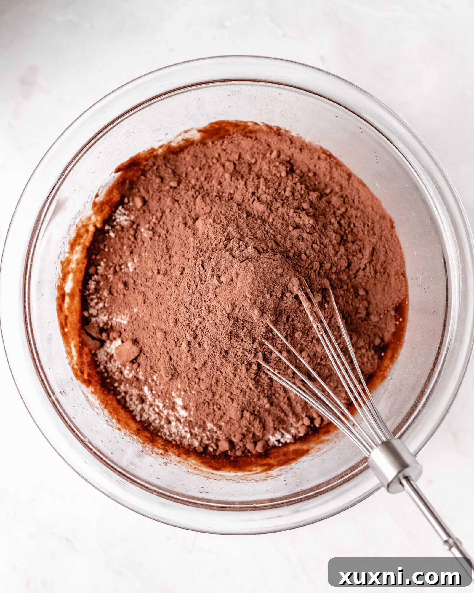 Dry ingredients (oat flour, cocoa powder, coconut sugar) added to the wet chocolate mixture, ready for mixing.