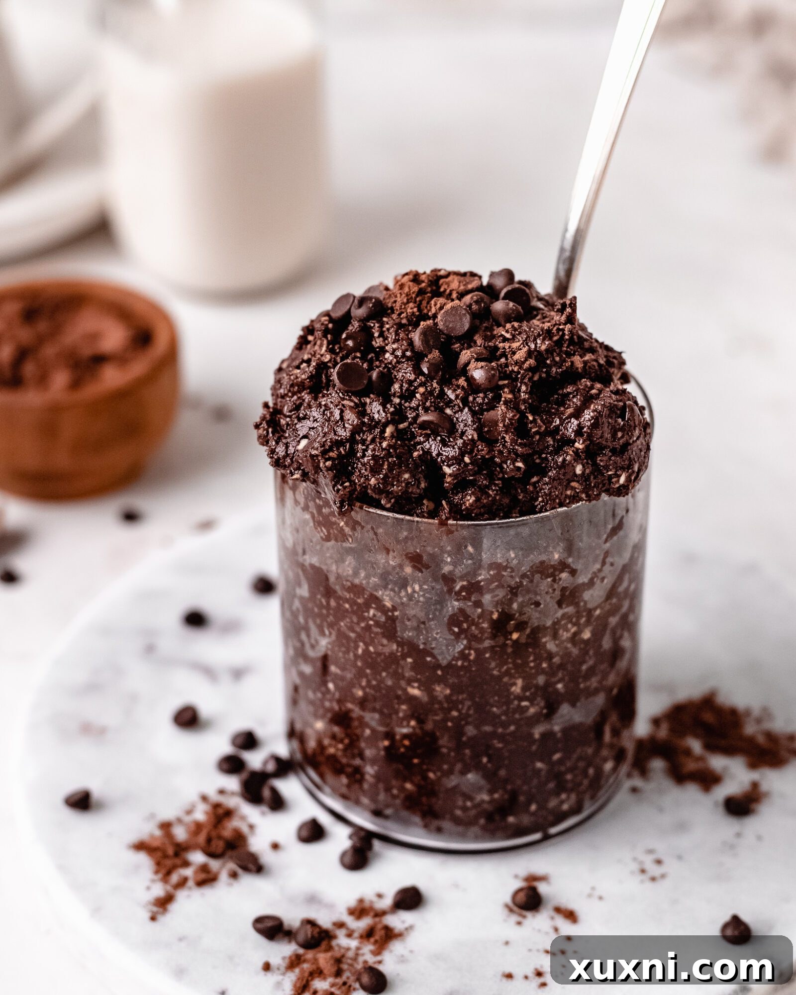 A small glass jar filled with the freshly made edible brownie batter, topped with extra chocolate chips.