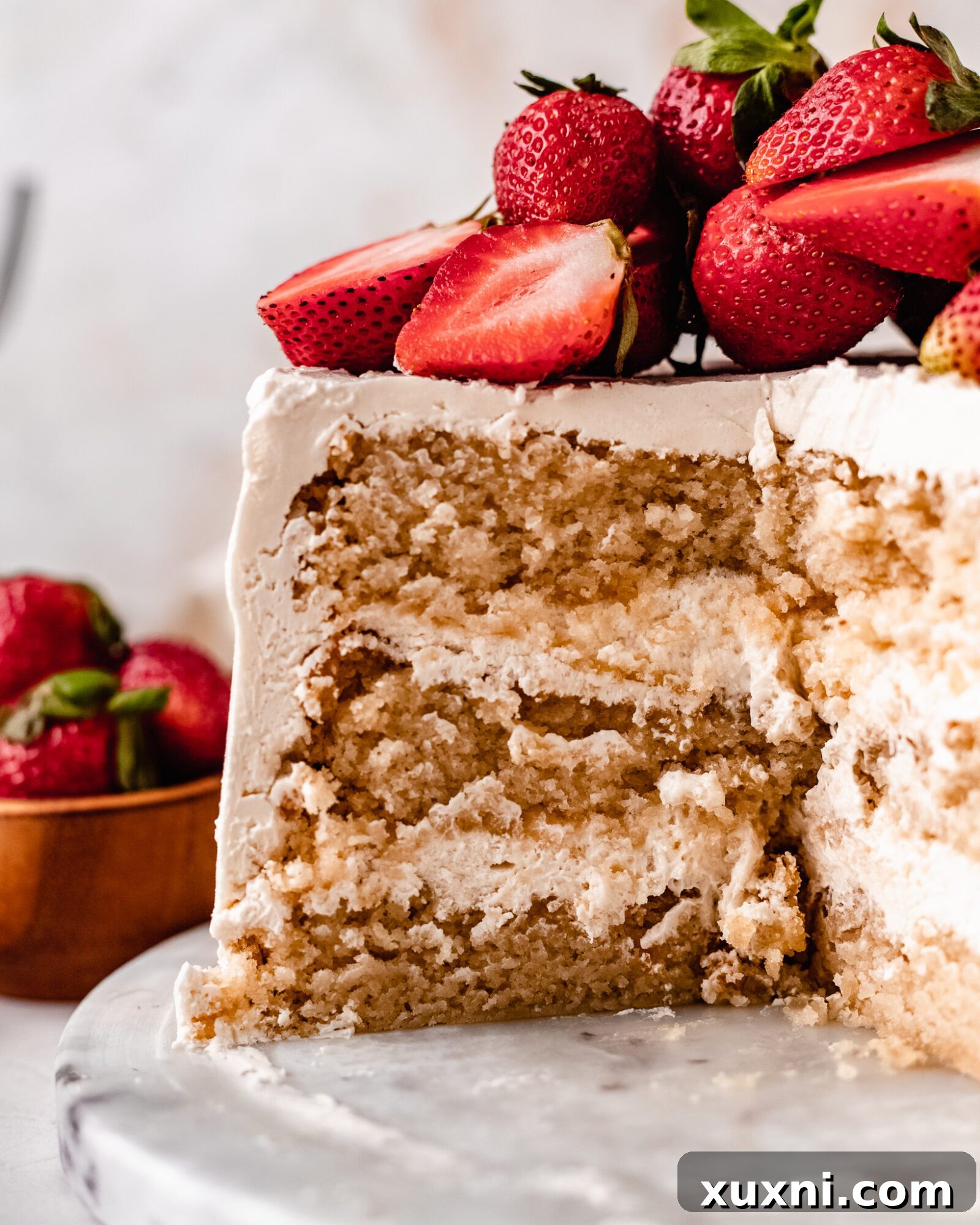 A beautifully frosted Strawberry Vanilla Chiffon Cake, whole and garnished with fresh strawberries, ready to be served.