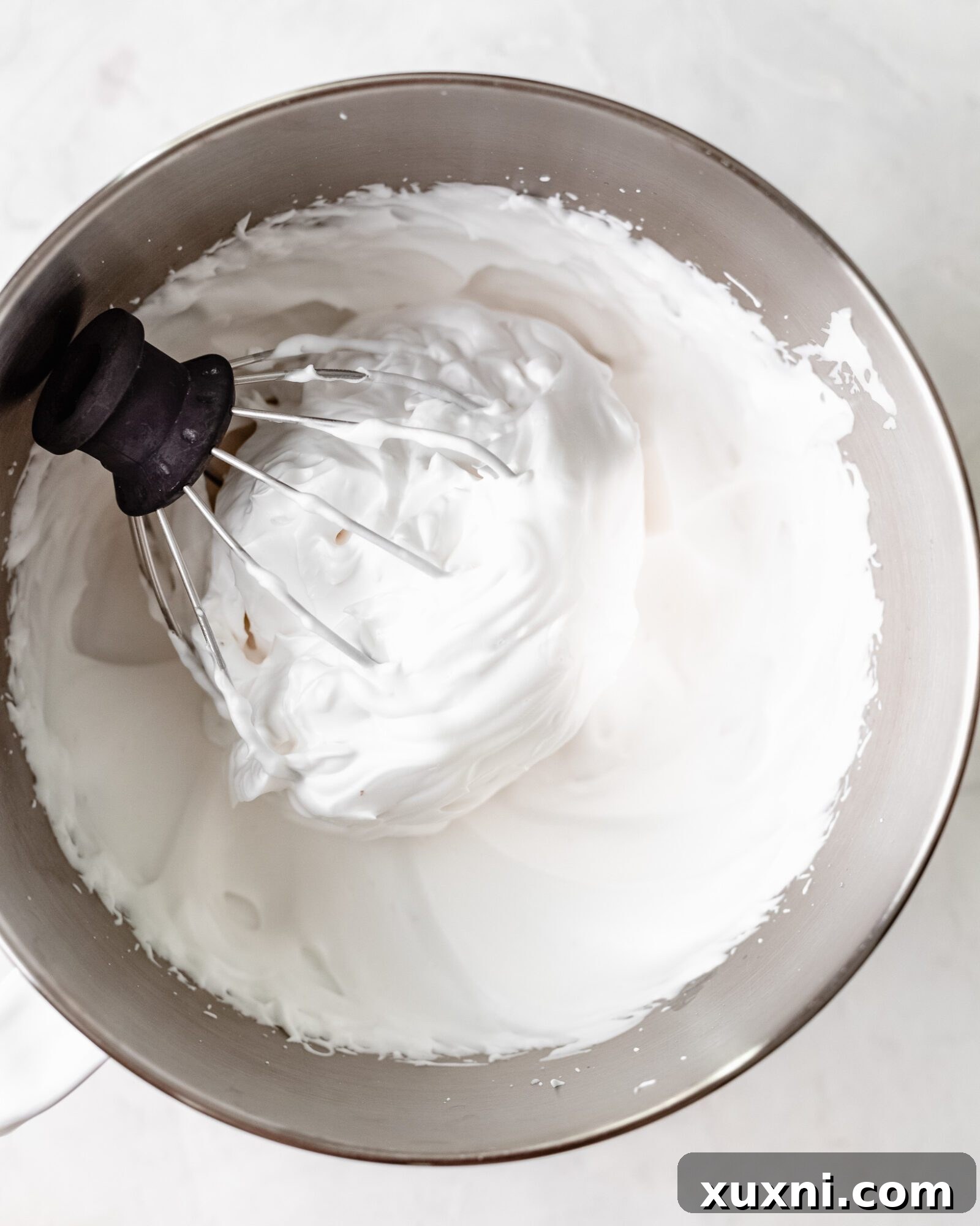 Close-up of perfectly whipped vegan meringue, showing stiff, glossy peaks ready for incorporation into cake batter.