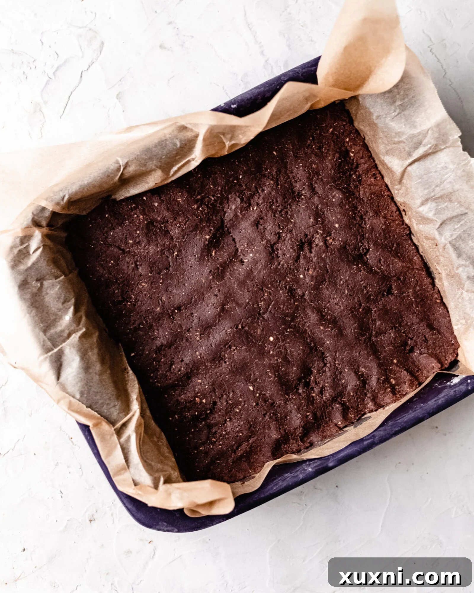 A pan filled with freshly pressed no-bake brownie batter, smoothed out and ready for chilling.