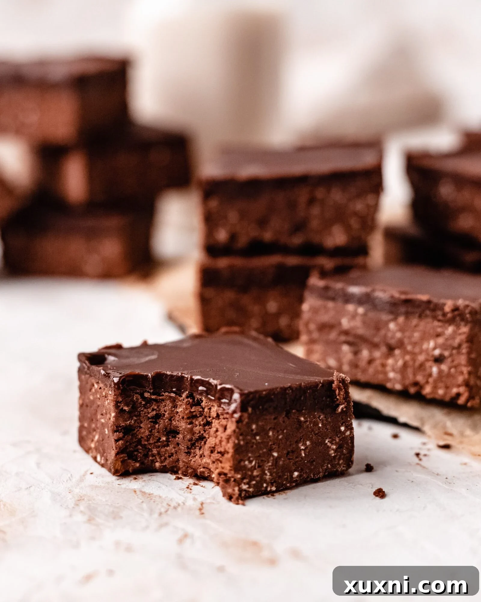 A healthy no-bake vegan brownie with a bite taken out, revealing its dense, fudgy interior.