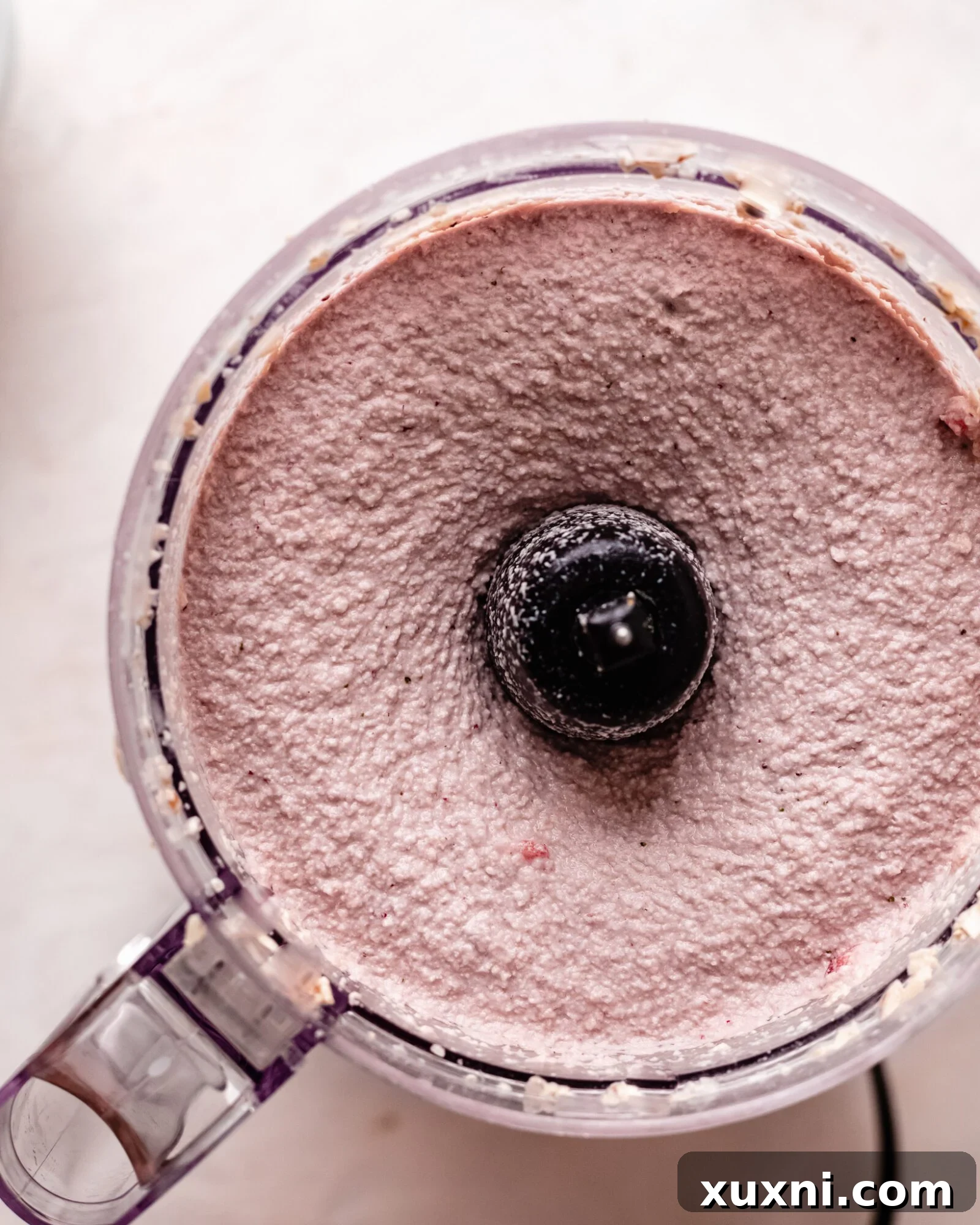 Blended vegan strawberry cheesecake filling in a food processor