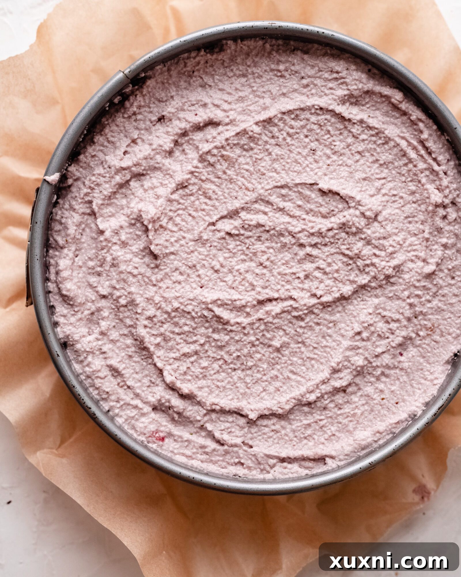 Smooth vegan strawberry cheesecake filling poured into the crust