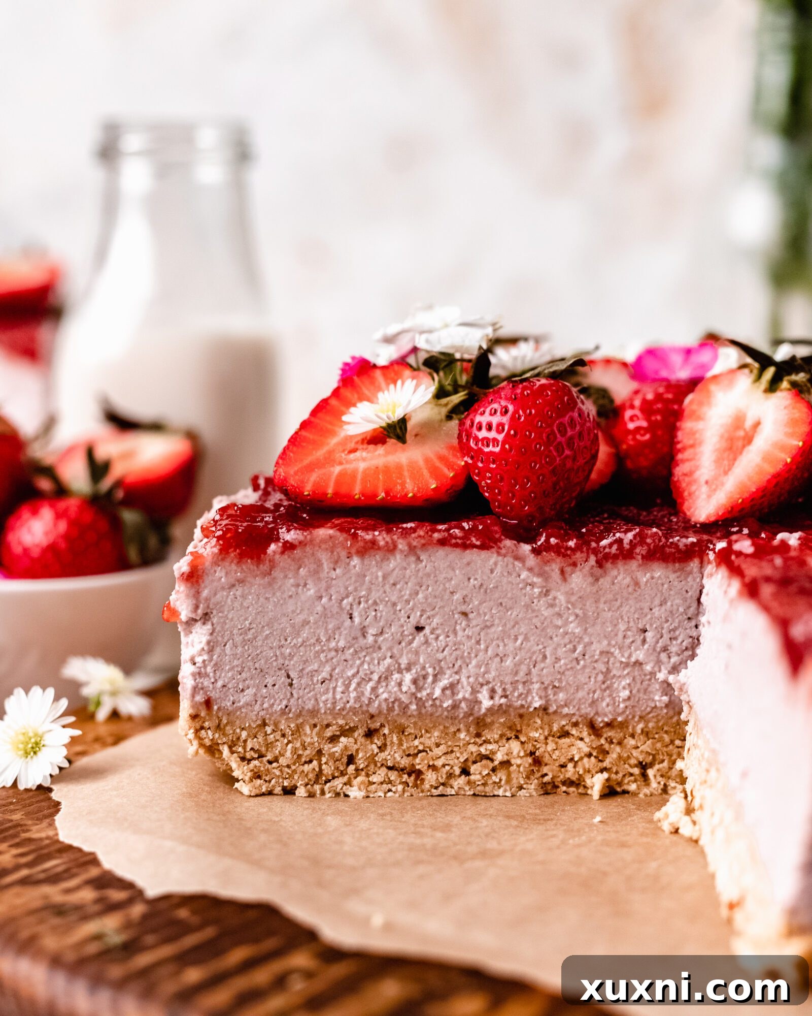 A close-up of a perfectly sliced no-bake vegan strawberry cheesecake with fresh garnishes