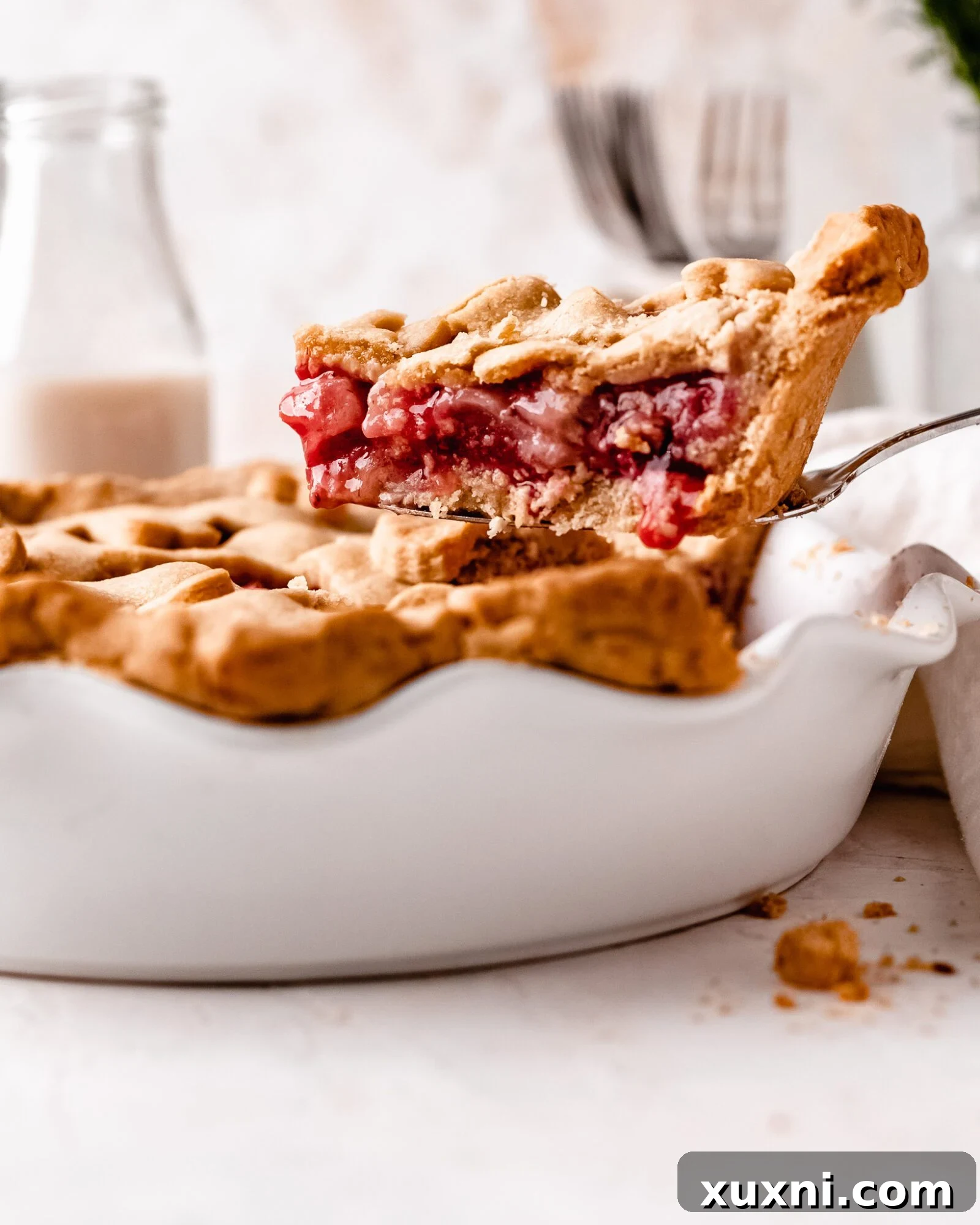 A close-up view of a baked strawberry pie slice, highlighting the gooey fruit and golden crust.