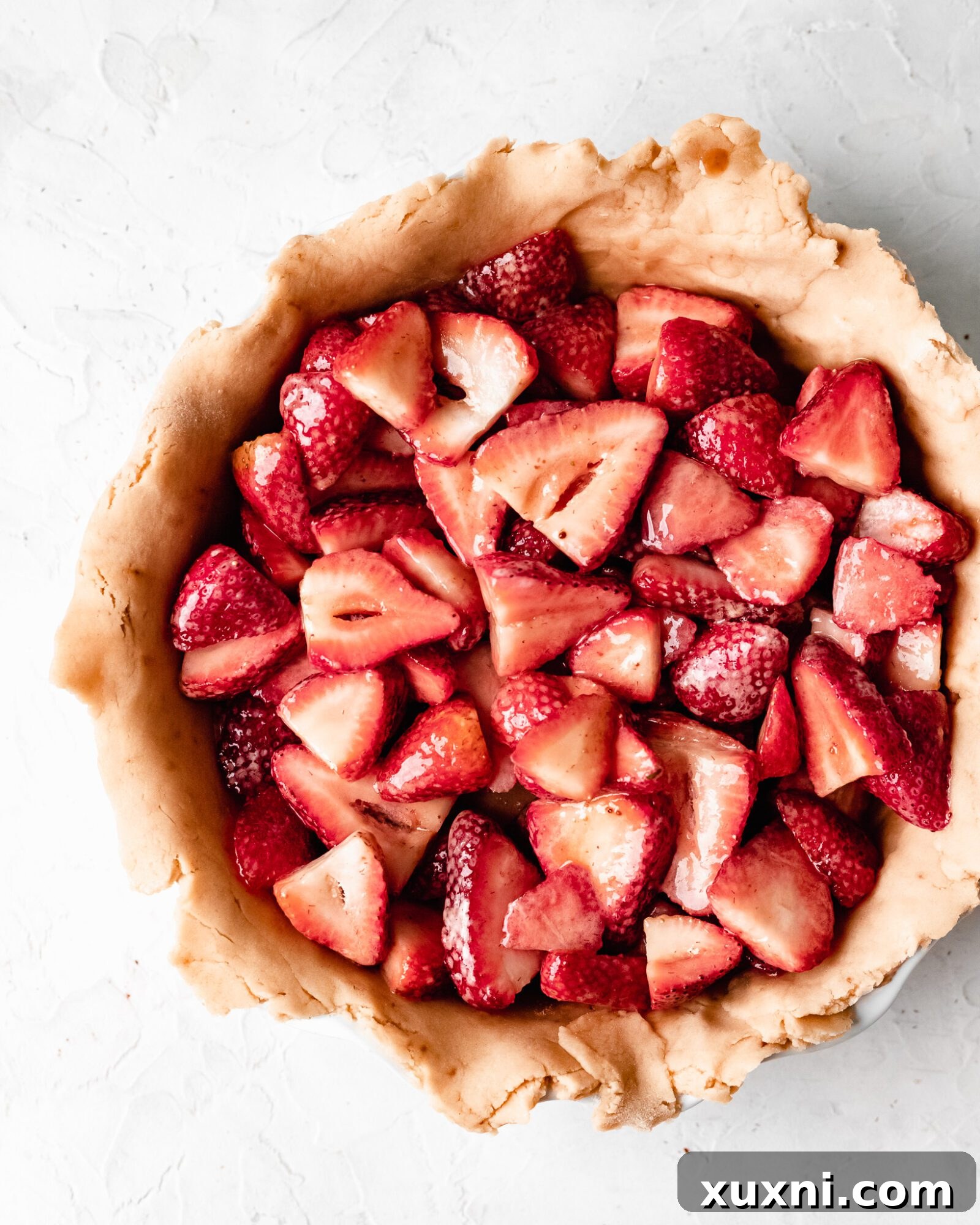 Another angle of the vibrant strawberry pie filling in a bowl, before going into the crust.