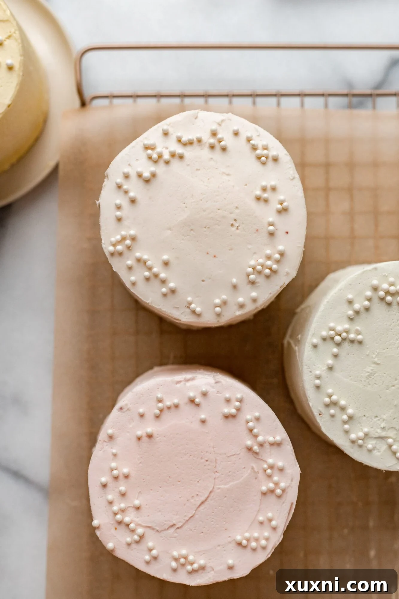 Mini cake layers cooling on parchment paper after baking, ready for frosting.