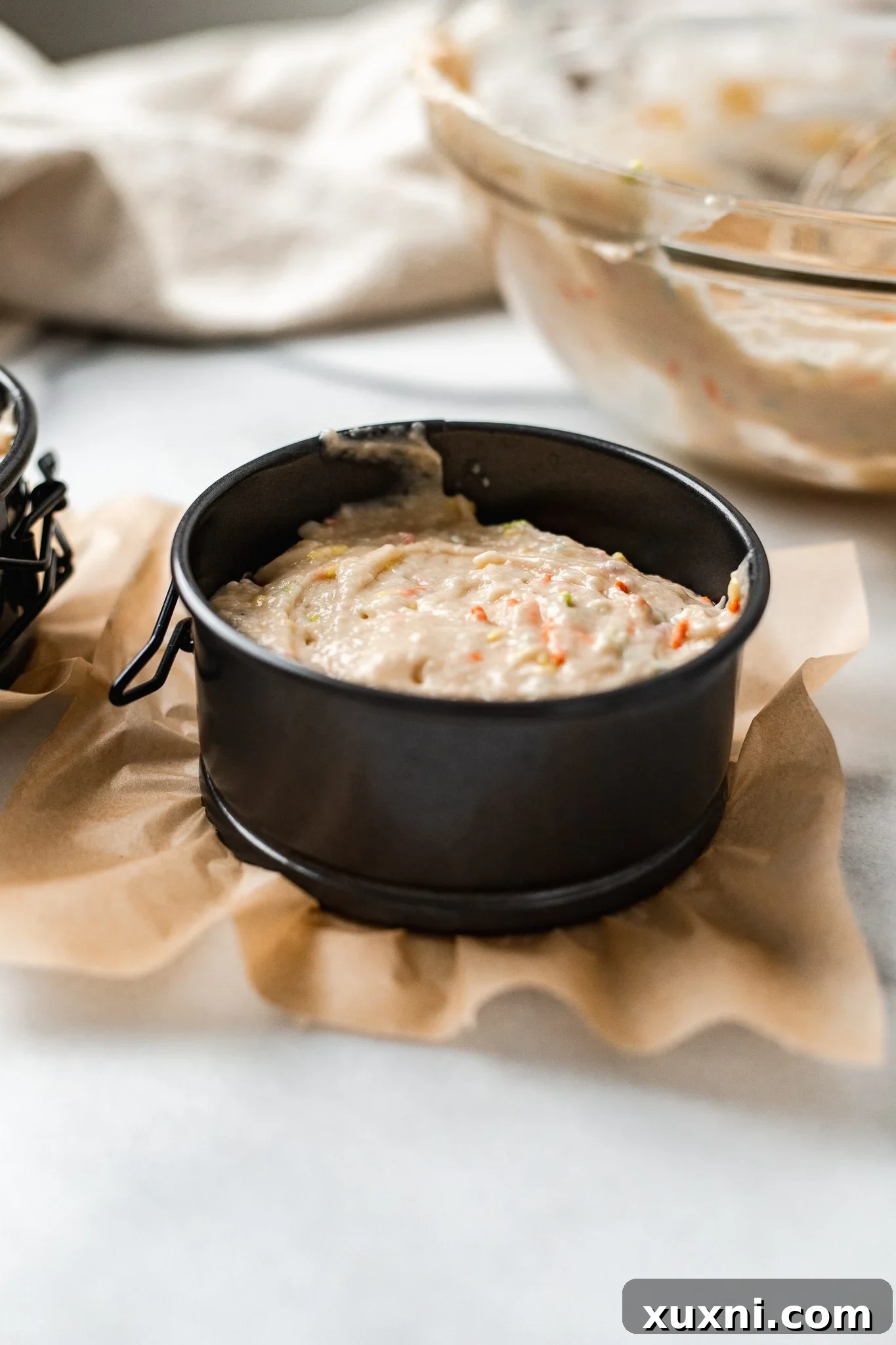 Cake batter baking in a round 4-inch cake pan, showing a slightly domed top.