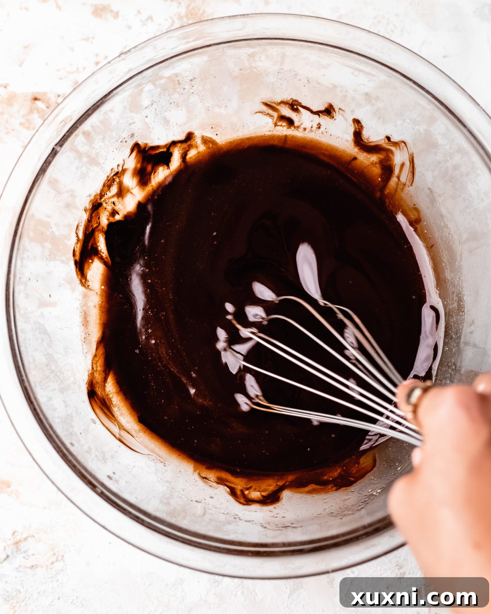 Melted vegan butter and chocolate being whisked together in a bowl.