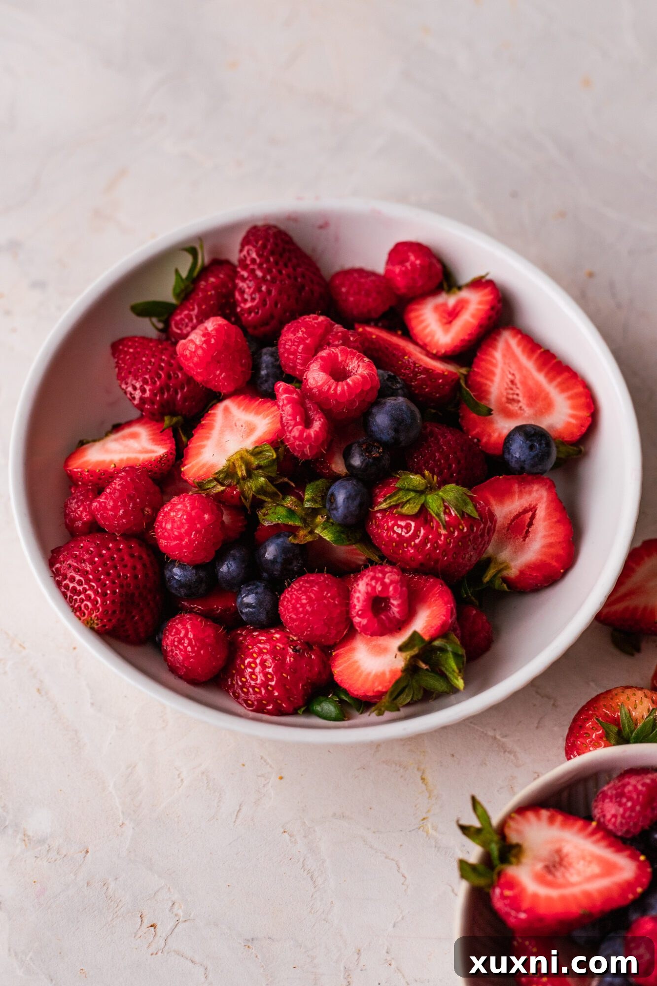 A bowl overflowing with fresh, vibrant mixed berries including strawberries, blueberries, raspberries, and blackberries.