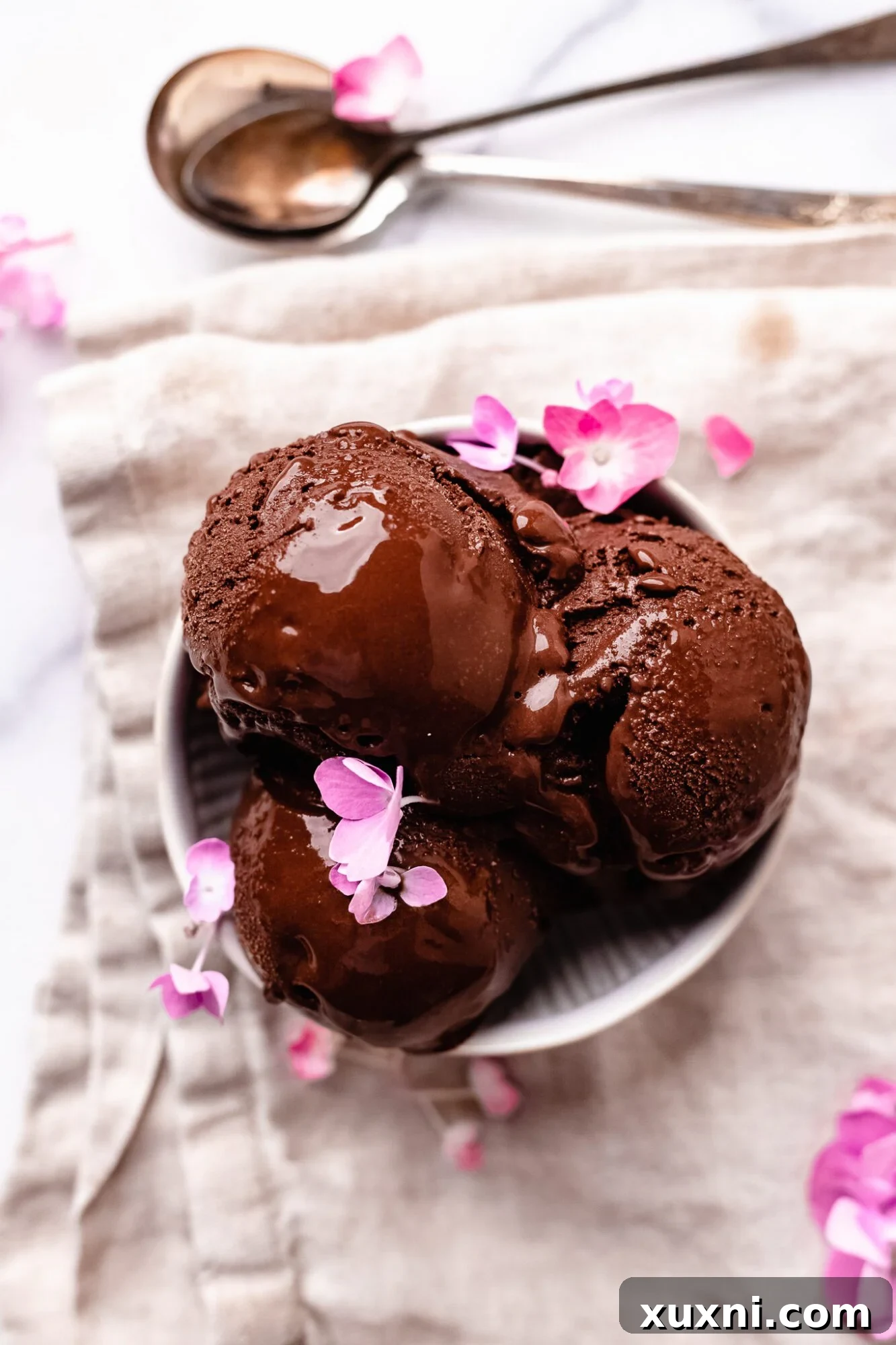 Several scoops of creamy vegan chocolate ice cream in a bowl, ready to be enjoyed.
