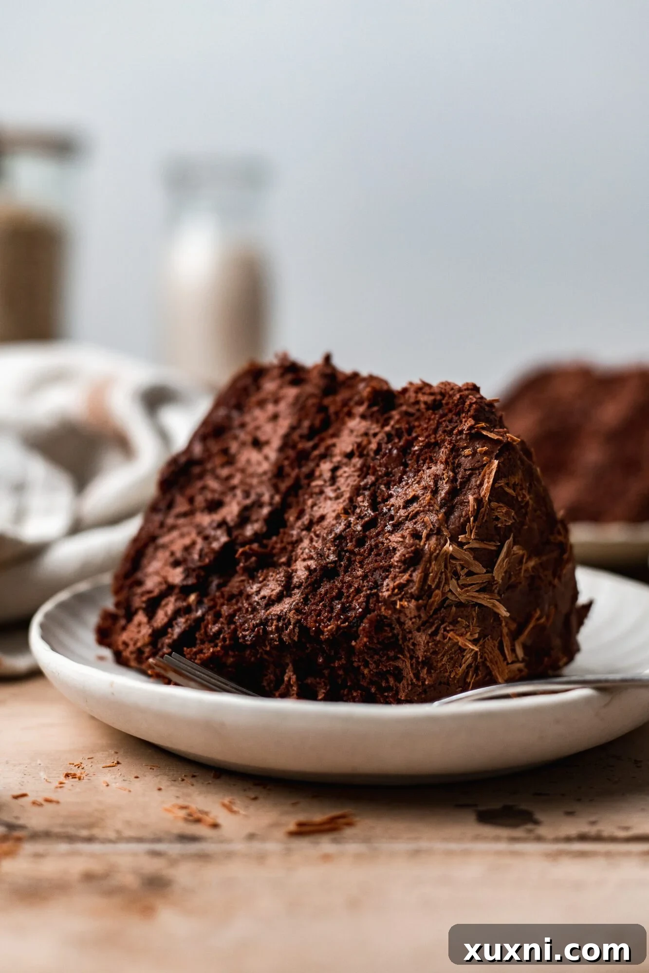 Irresistible Vegan Gluten-Free Chocolate Oat Cake 8 A beautiful slice of vegan gluten-free chocolate cake with delicate frosting and toppings.