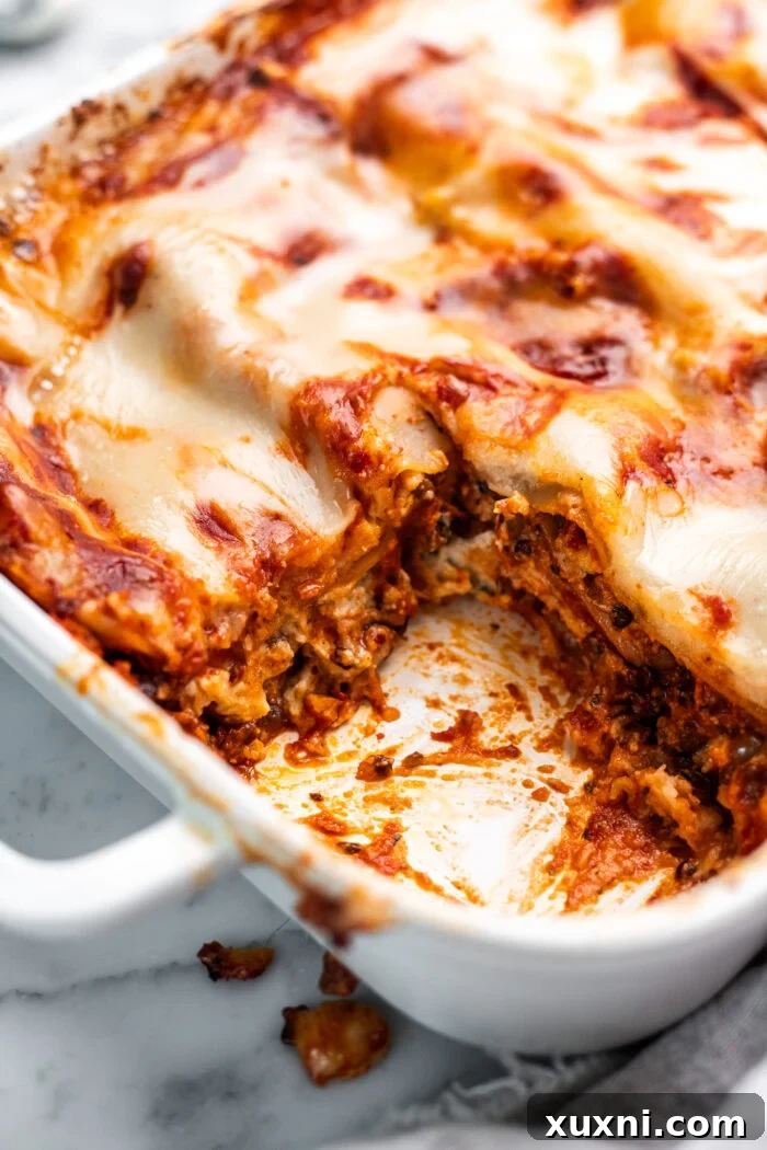 Close up of a freshly sliced vegan lasagna, revealing gooey cheese and rich lentil layers