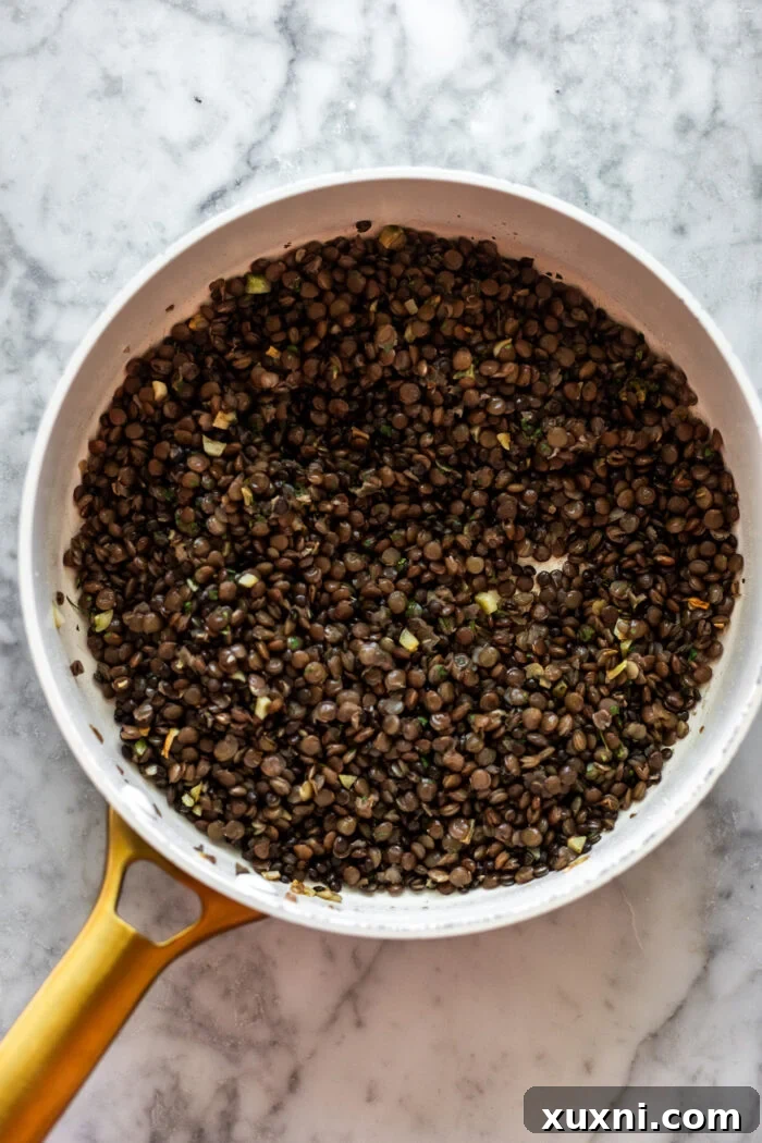 Lentils being cooked with garlic in a saucepan