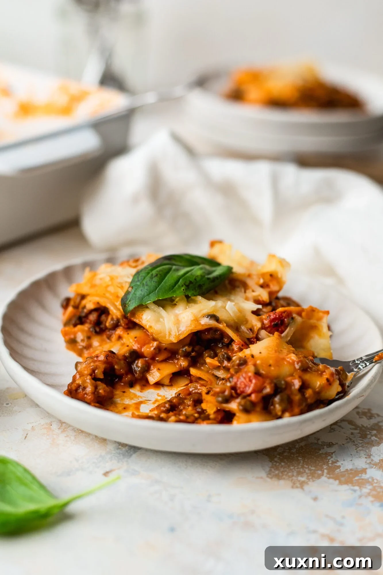 A serving of homemade vegan lasagna on a plate, garnished with fresh basil