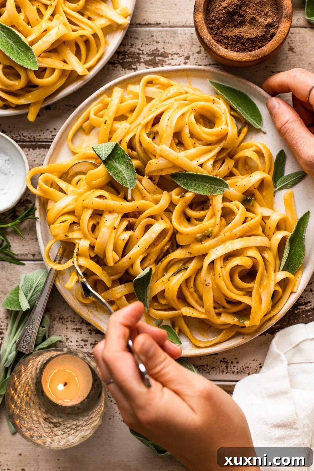 hand twirling vegan pumpkin pasta with fresh sage
