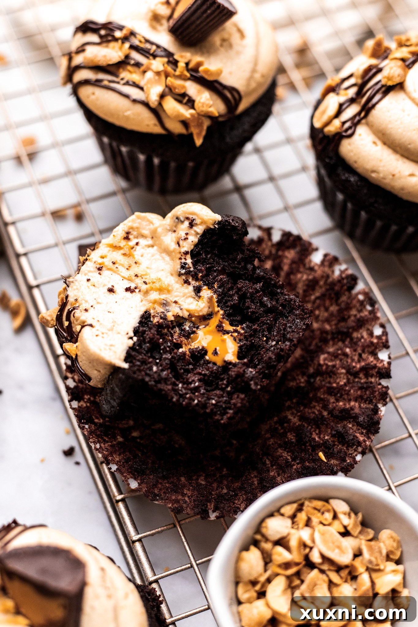 bitten chocolate peanut butter cupcake on cooling rack showing frosting