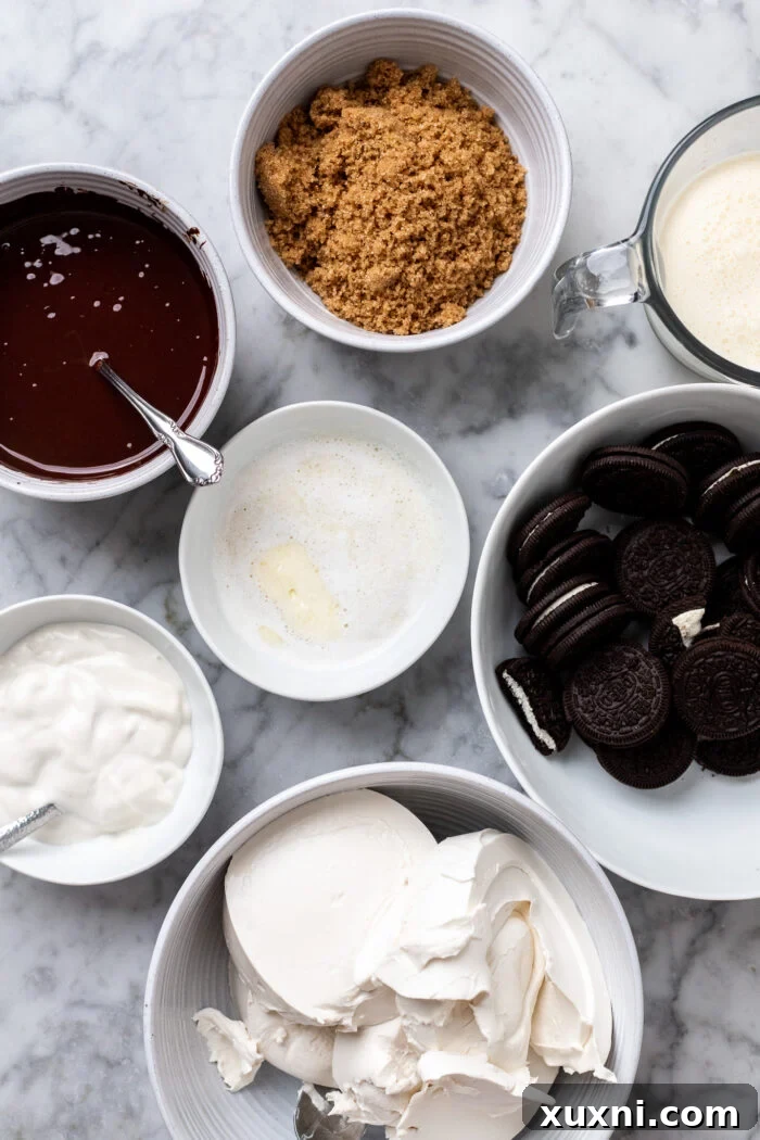 Collection of ingredients for no-bake vegan chocolate cheesecake, including vegan cream cheese, chocolate, cookies, and butter