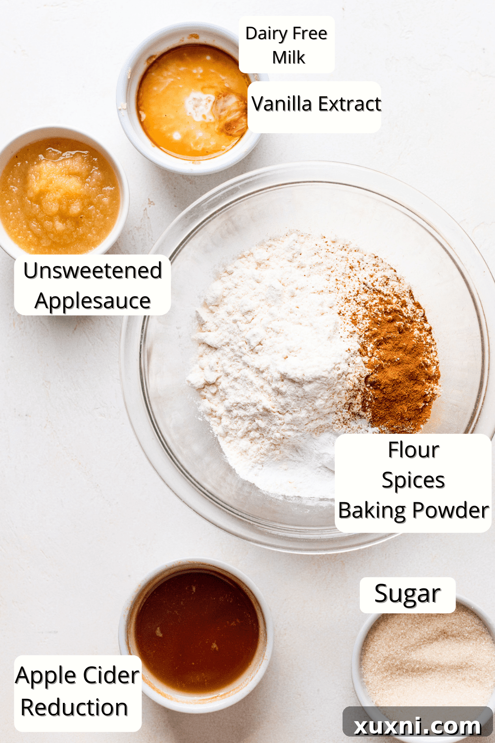 various vegan apple cider donut ingredients laid out, including flour, spices, applesauce, and apple cider