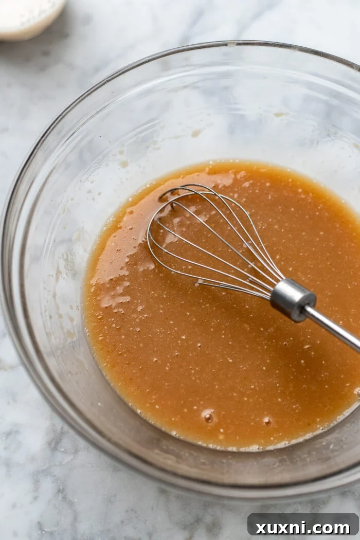 wet ingredients for vegan apple cider donuts being whisked together in a bowl