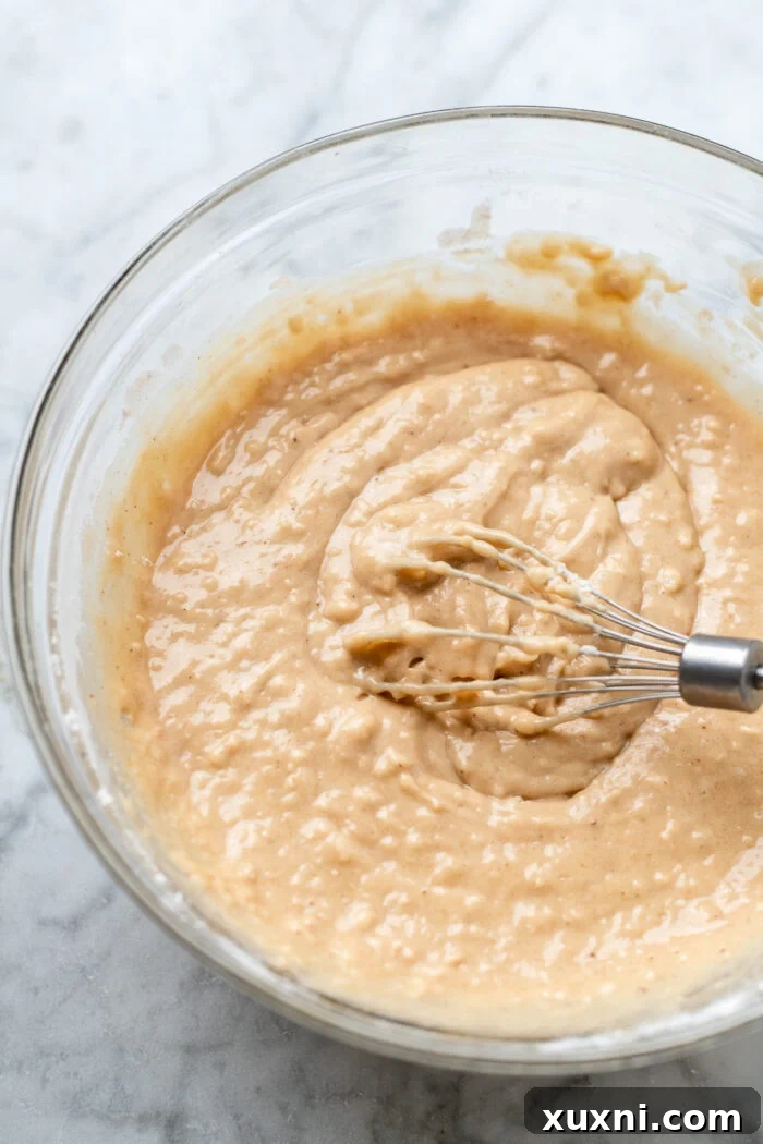 dry ingredients being folded into the wet batter for vegan apple cider donuts