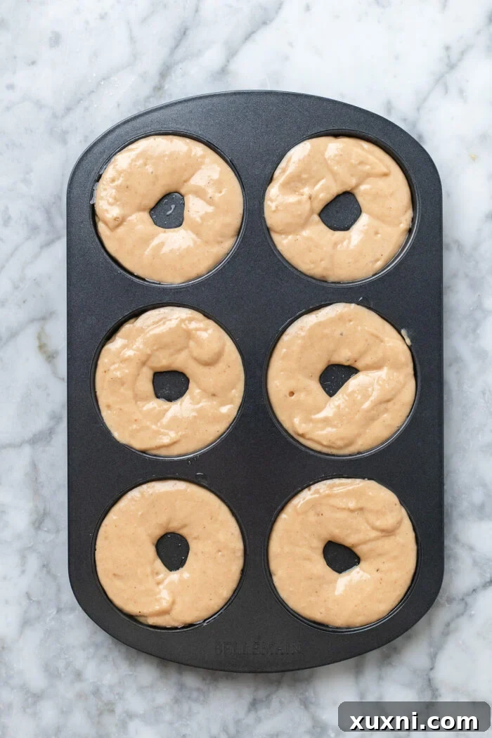 donut pan filled with vegan apple cider donut batter, ready for baking