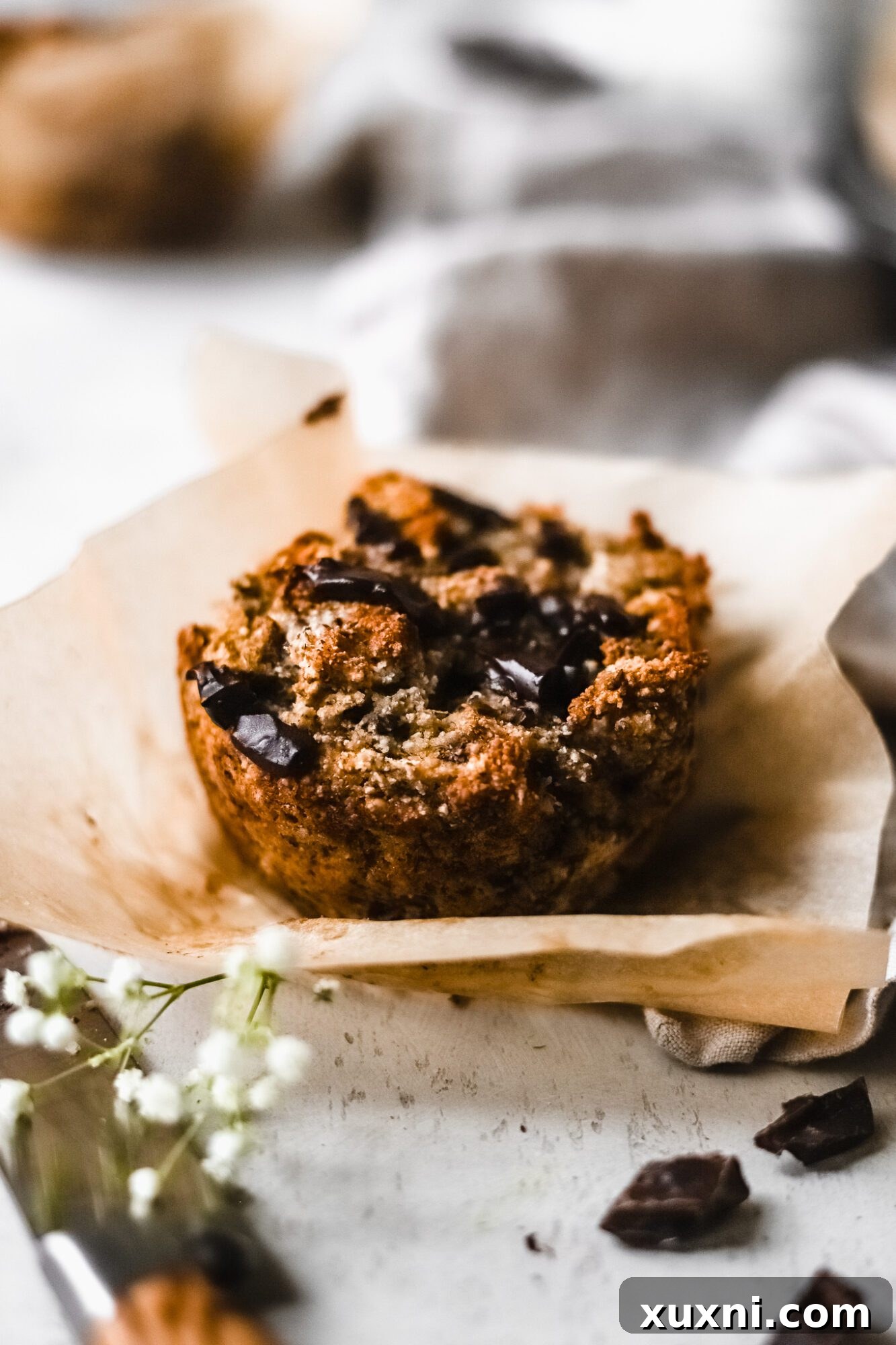 A single Paleo banana muffin resting on parchment paper, highlighting its perfectly baked crust.