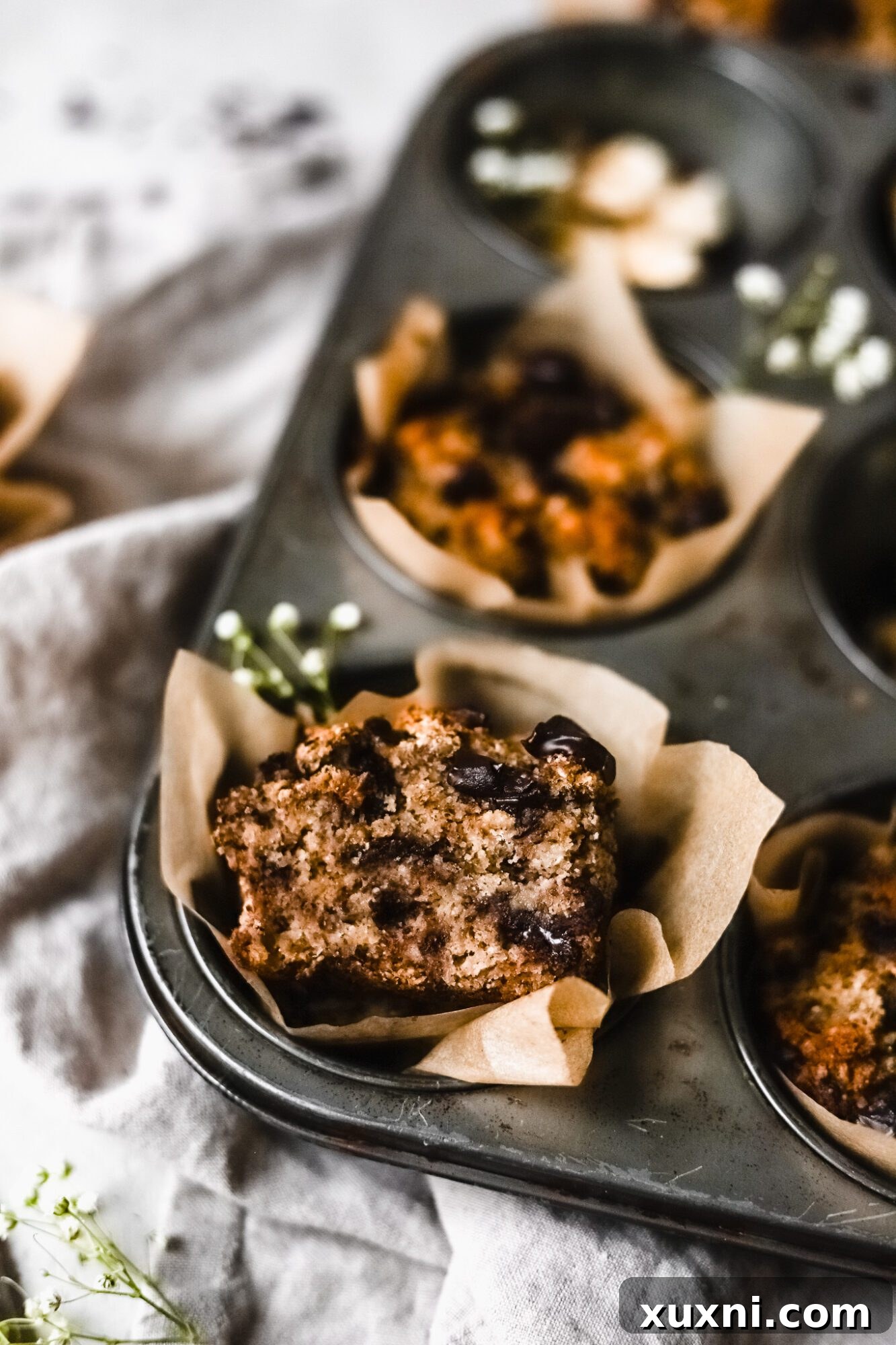 A perfectly sliced Paleo banana muffin, showcasing its light, airy texture and generous chocolate chip distribution.