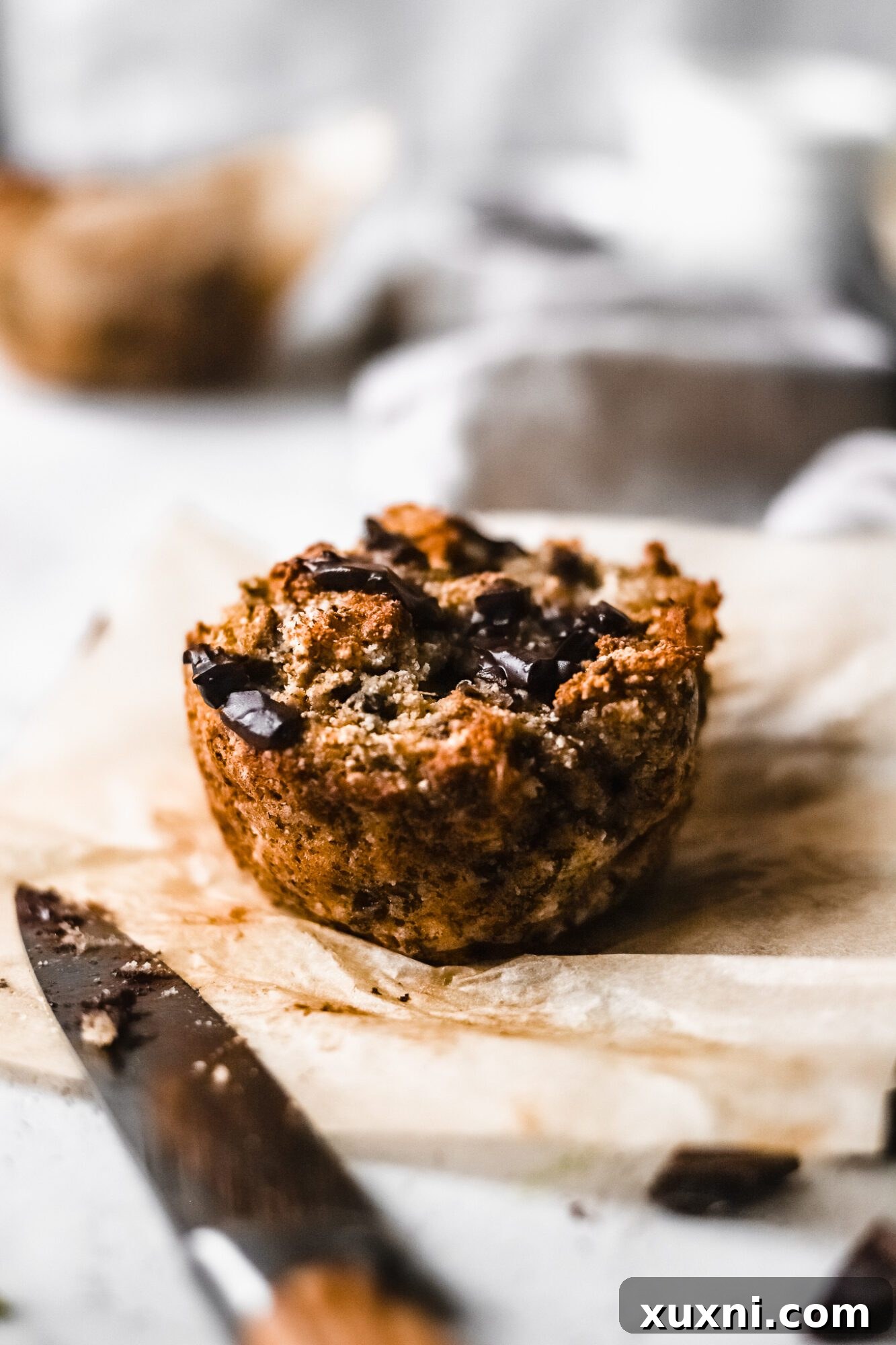 A Paleo banana muffin with a knife, ready to be enjoyed.