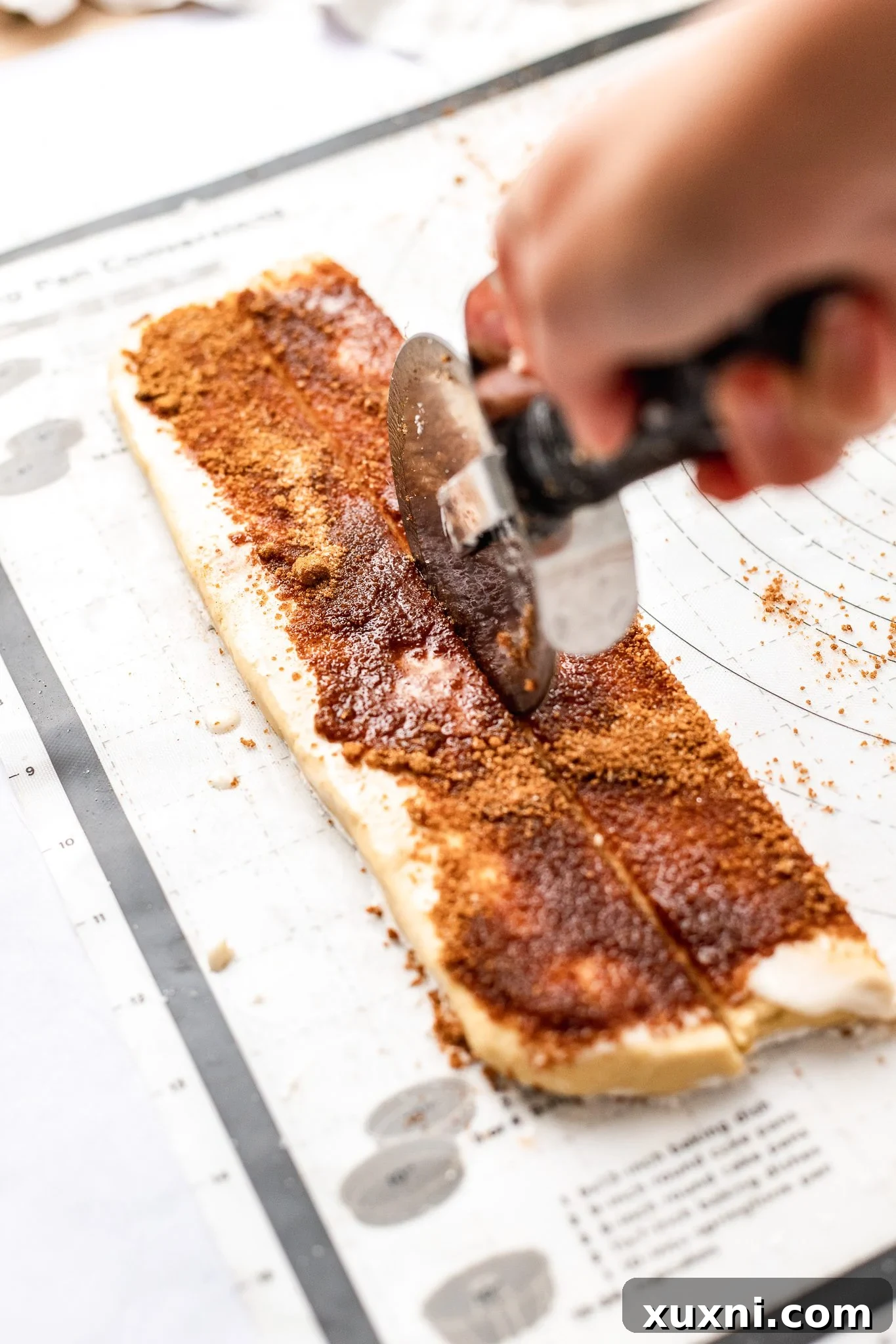 pizza cutter slicing cinnamon roll dough