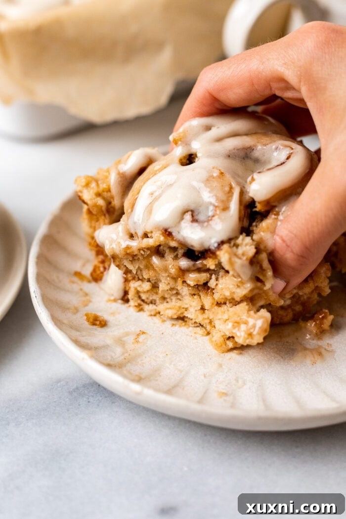 hand grabbing cinnamon rolls on a plate