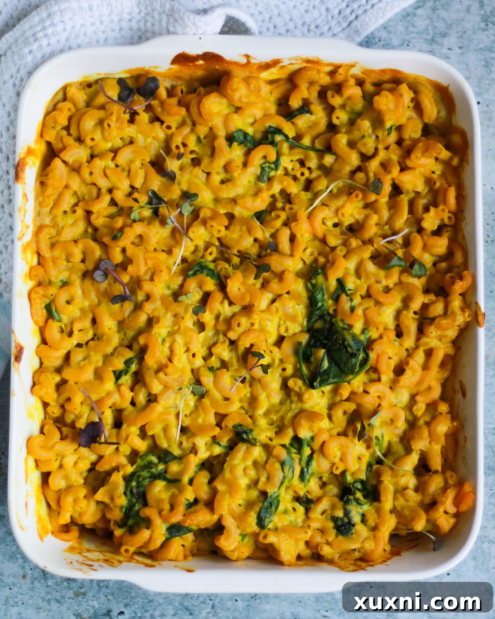 Overhead shot of rich, creamy vegan macaroni and cheese in a baking dish, garnished with fresh herbs.