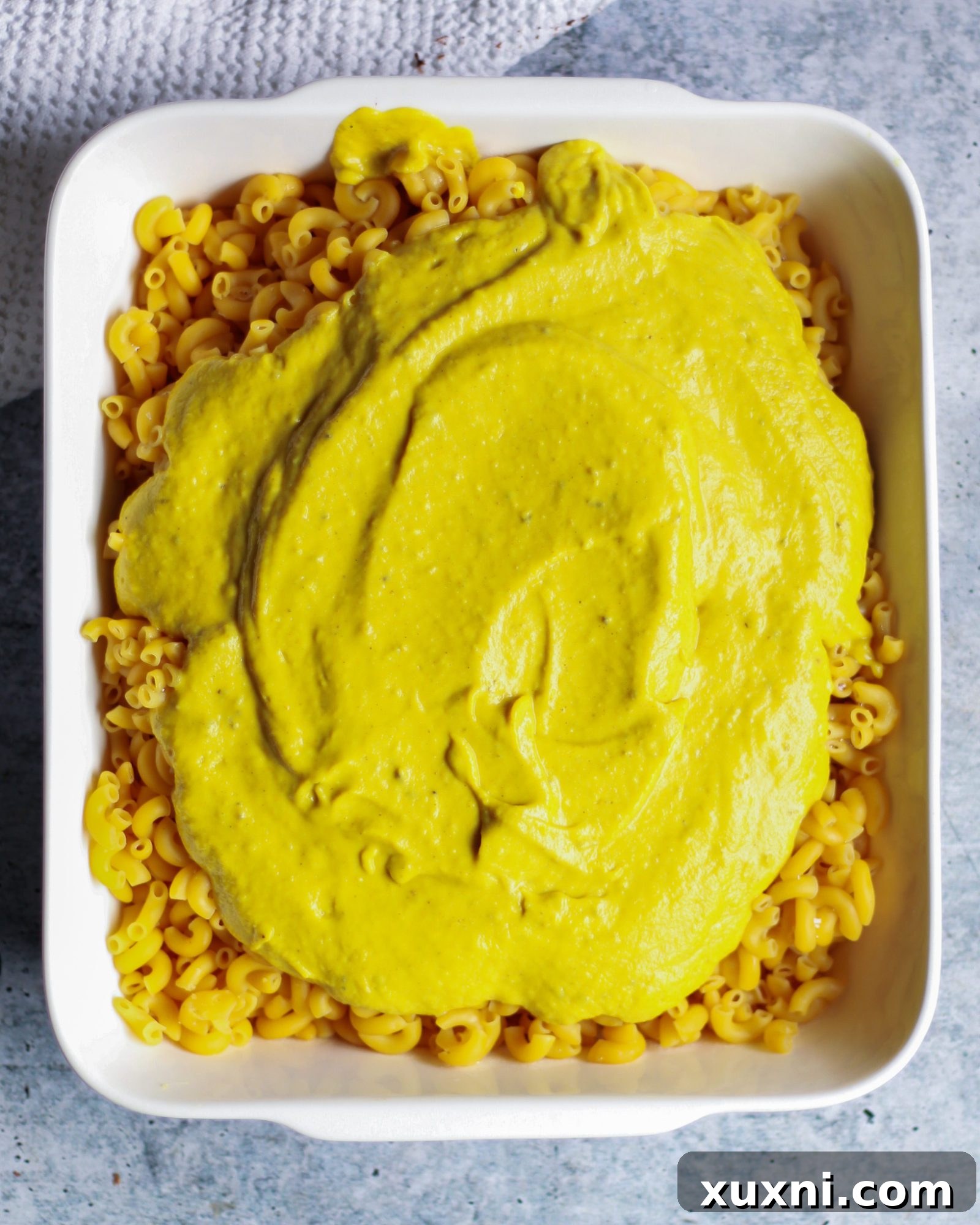 Close-up of macaroni pasta generously coated in a golden, creamy vegan cheese sauce.