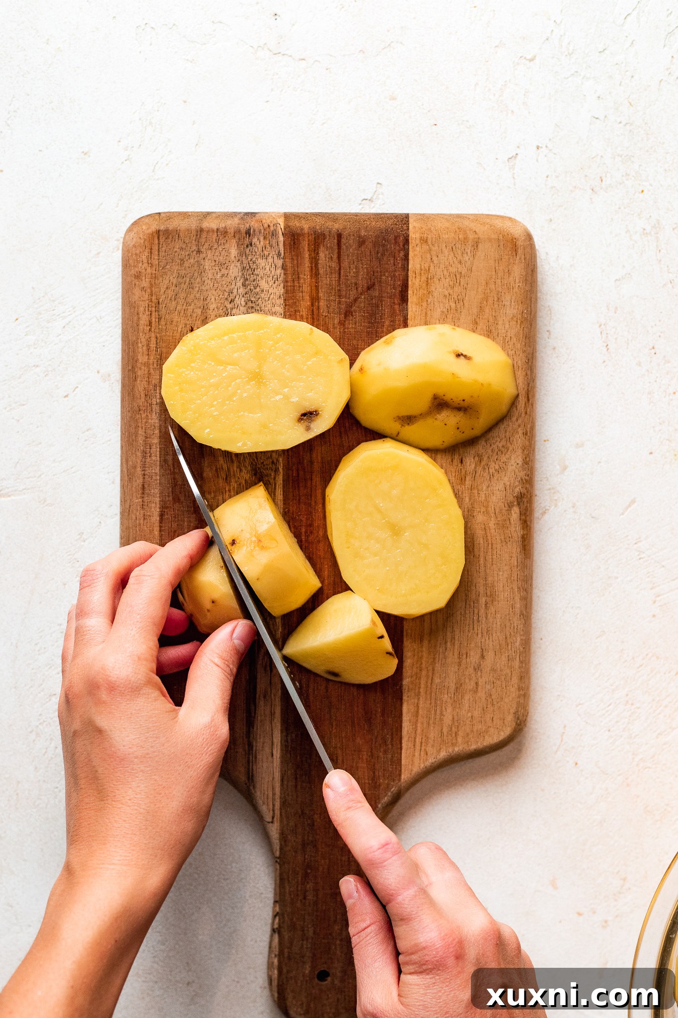 Slicing potatoes for vegan mashed potatoes, ensuring even cooking for a creamy result.