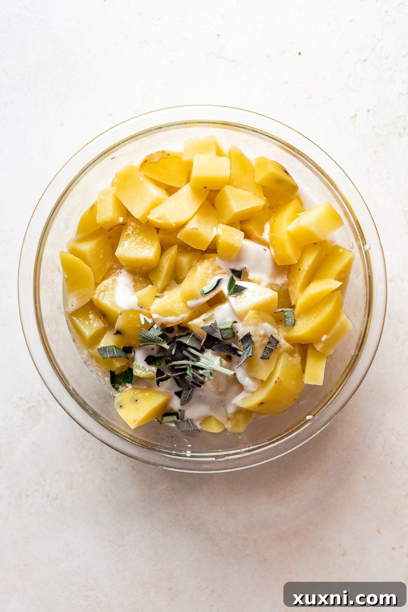 Boiled potatoes in a bowl after straining, with a note to save some of the starchy water for added creaminess.