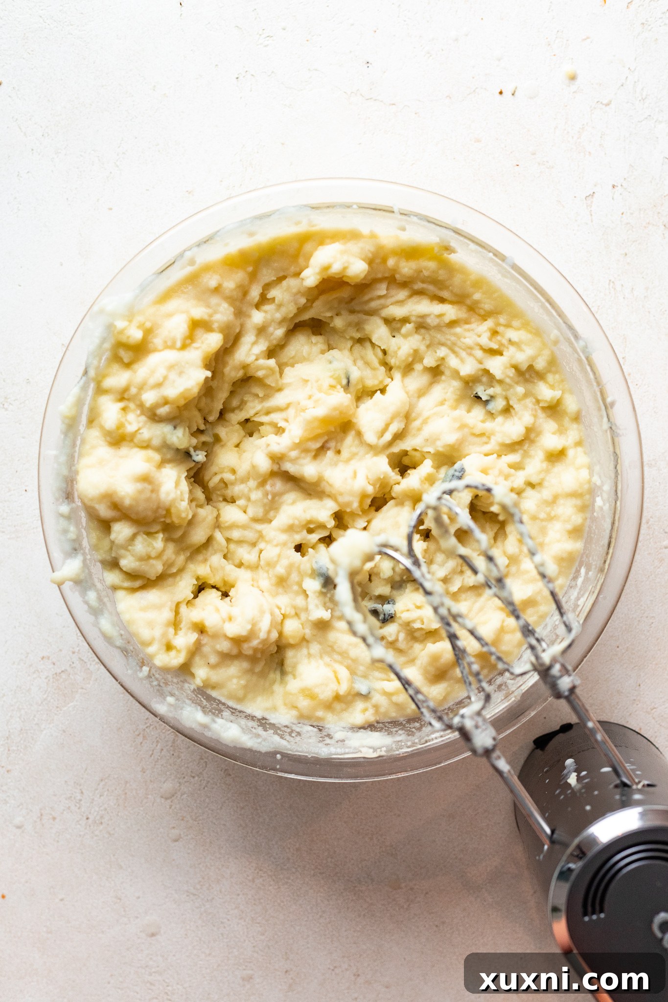 Partially mixed vegan mashed potatoes, illustrating the creamy texture before final serving with herbs and gravy.