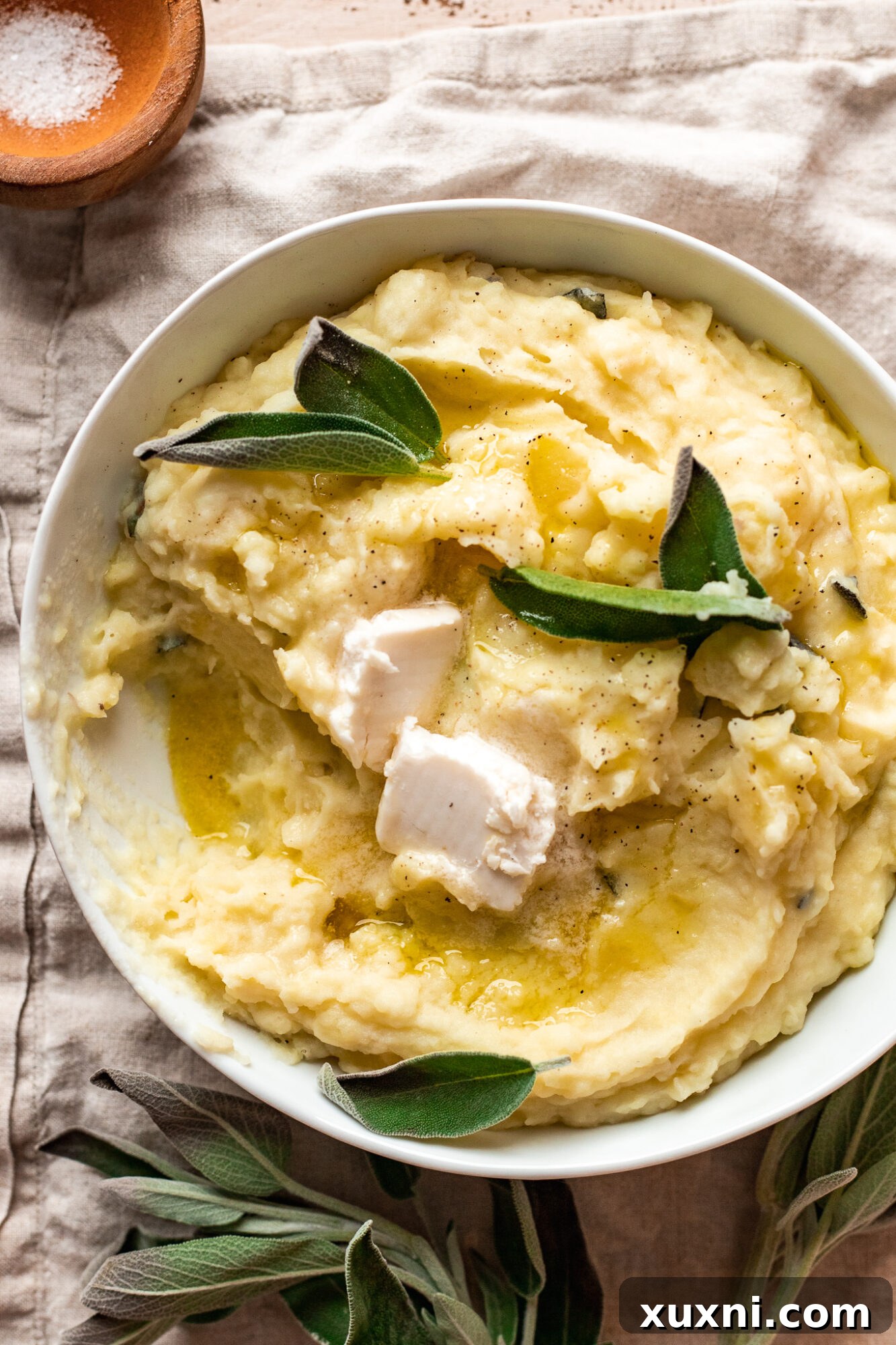 A serving of creamy vegan mashed potatoes drizzled with gravy, garnished with fresh herbs, showcasing its rich texture.