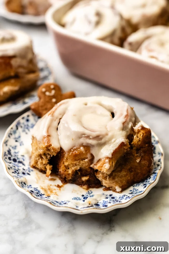 A close-up of a gingerbread cinnamon roll with a bite taken out, showing the gooey center.