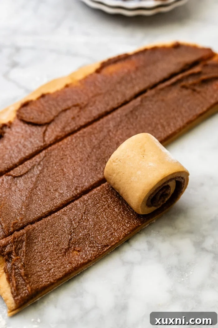 Dough sliced into strips, ready to be rolled into individual cinnamon rolls.